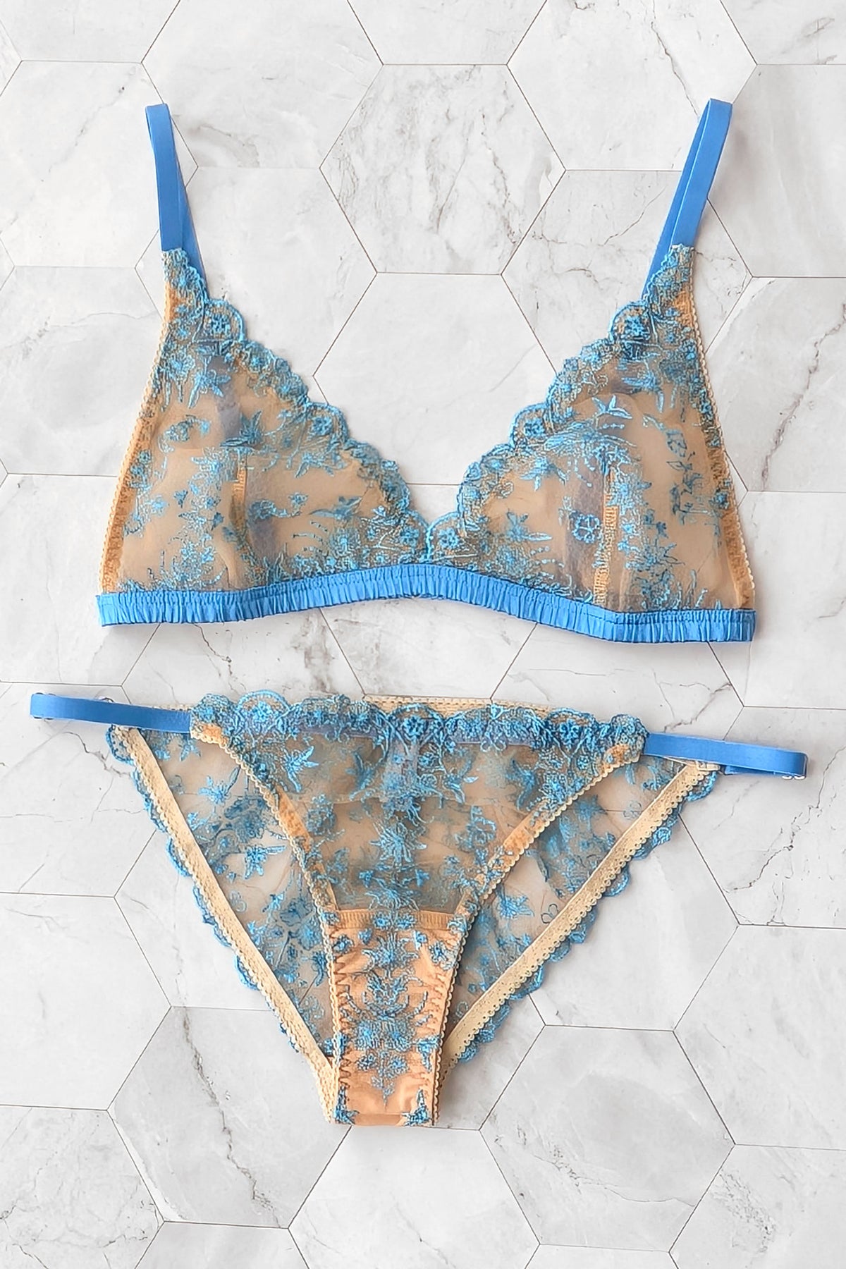 A two-piece sheer lace lingerie set featuring a bralette and matching panty in light blue and nude mesh with blue straps