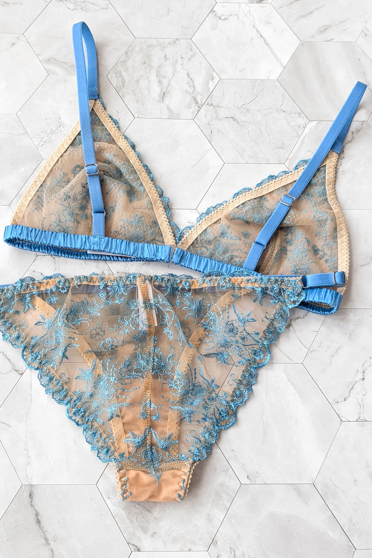 Back view of a two-piece sheer lace lingerie set in light blue silk satin and beige tulle, with blue elastic adjustable straps