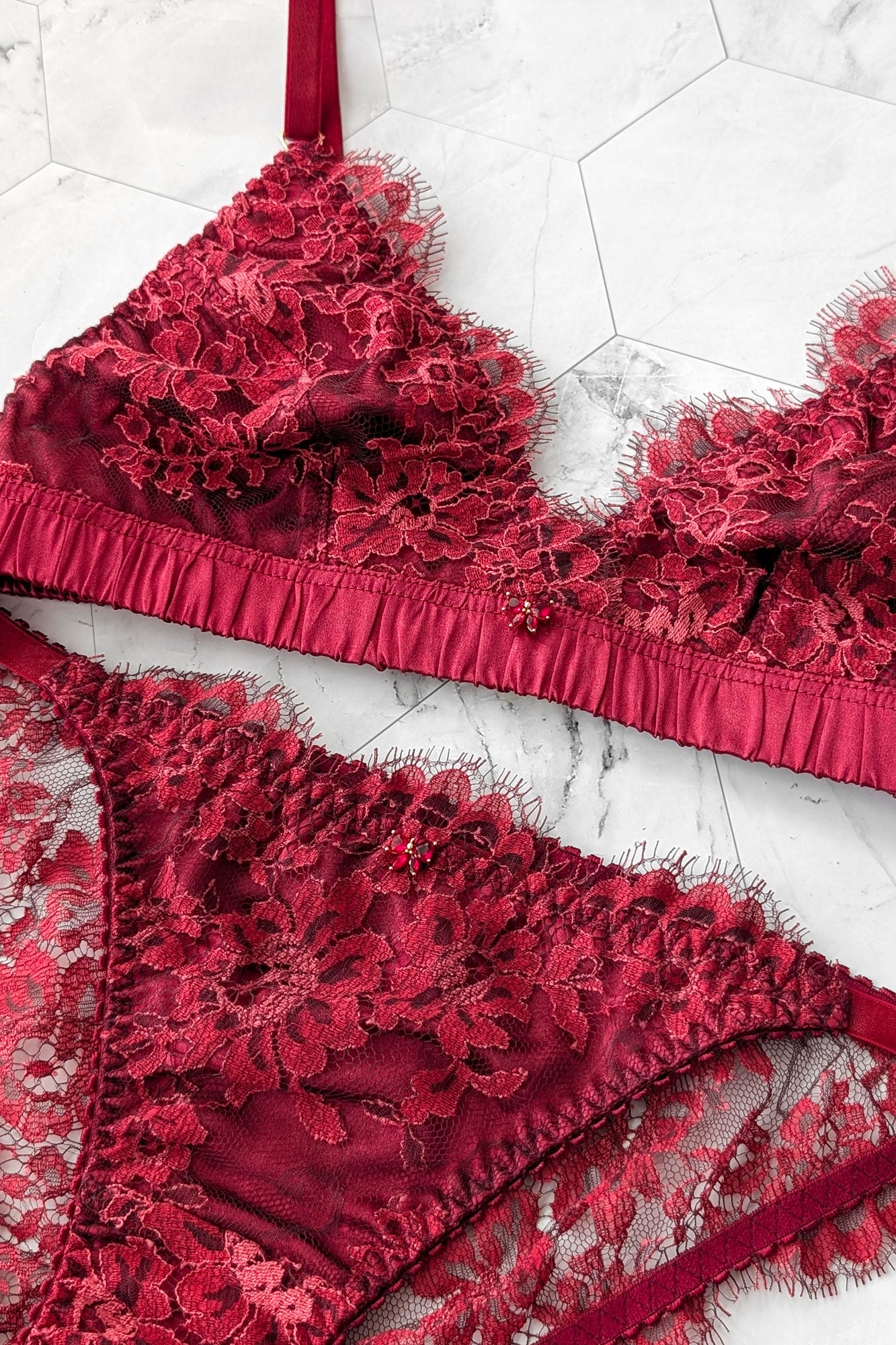Closeup of a red lace bra and knickers set with 100% silk linings and red bow jewels