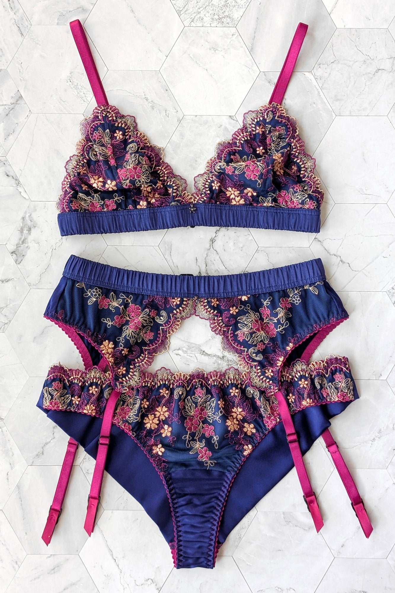 Vintage inspired 3-piece lingerie set including a blue silk bralette, a retro garter belt with pink straps, and embroidered cheeky panties with silk linings