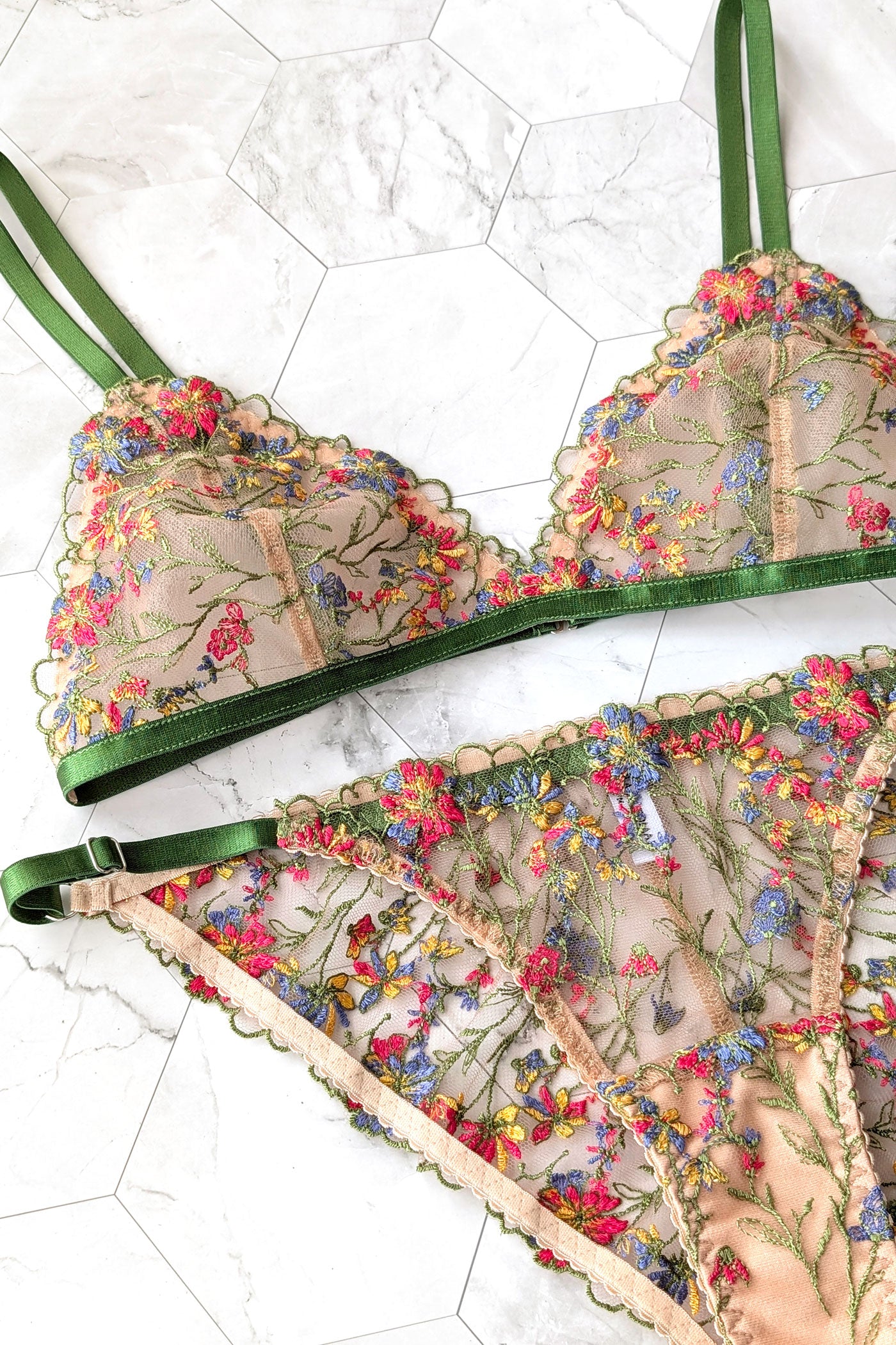 Colorful floral bra and underwear set in nude with green, blue, red, and yellow flowers scattered across the sheer tulle