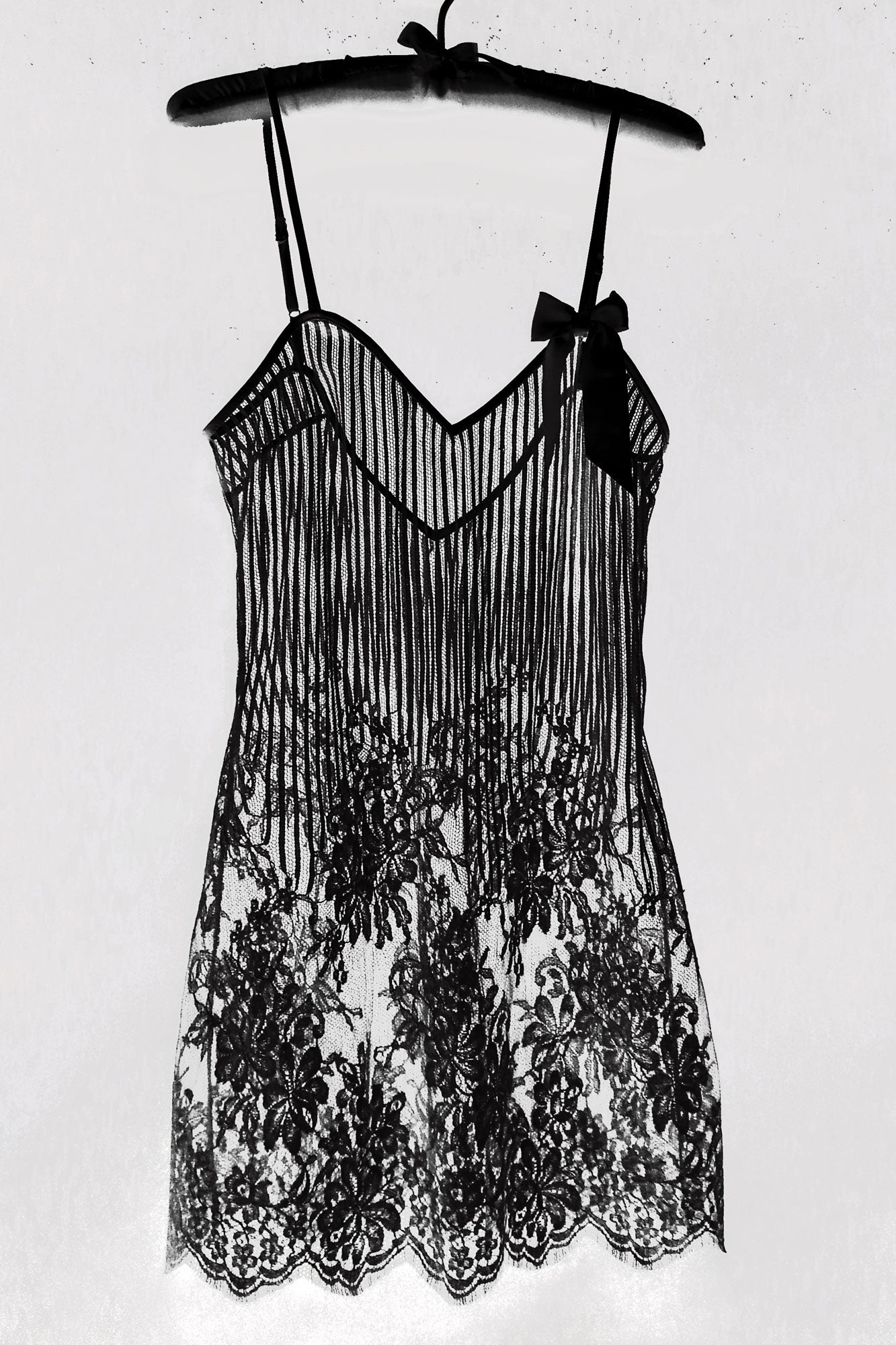 Black luxury lace slip dress on a hanger against a white background