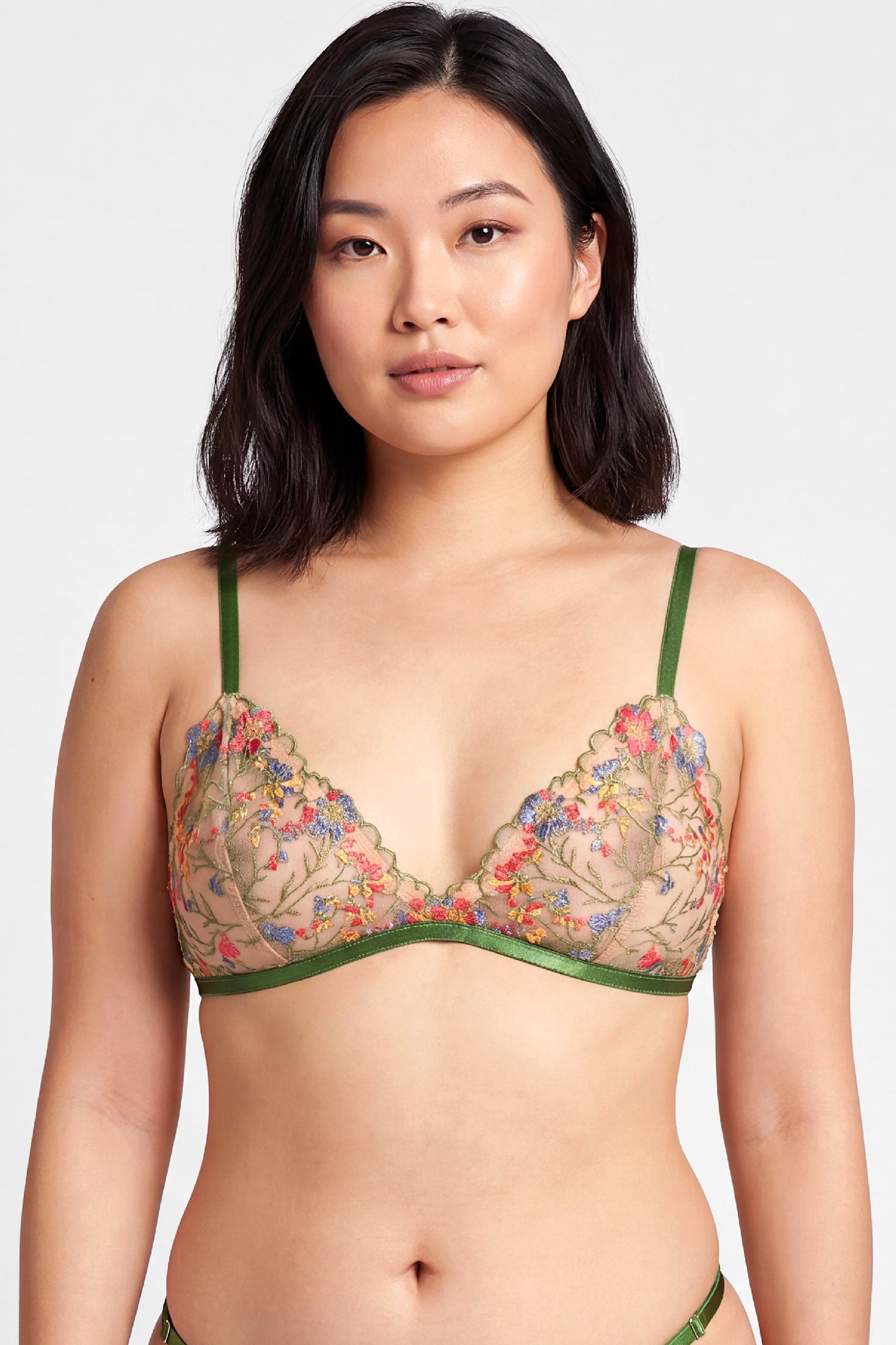 Embroidered floral bralette with green straps and red and blue flowers on nude tattoo net
