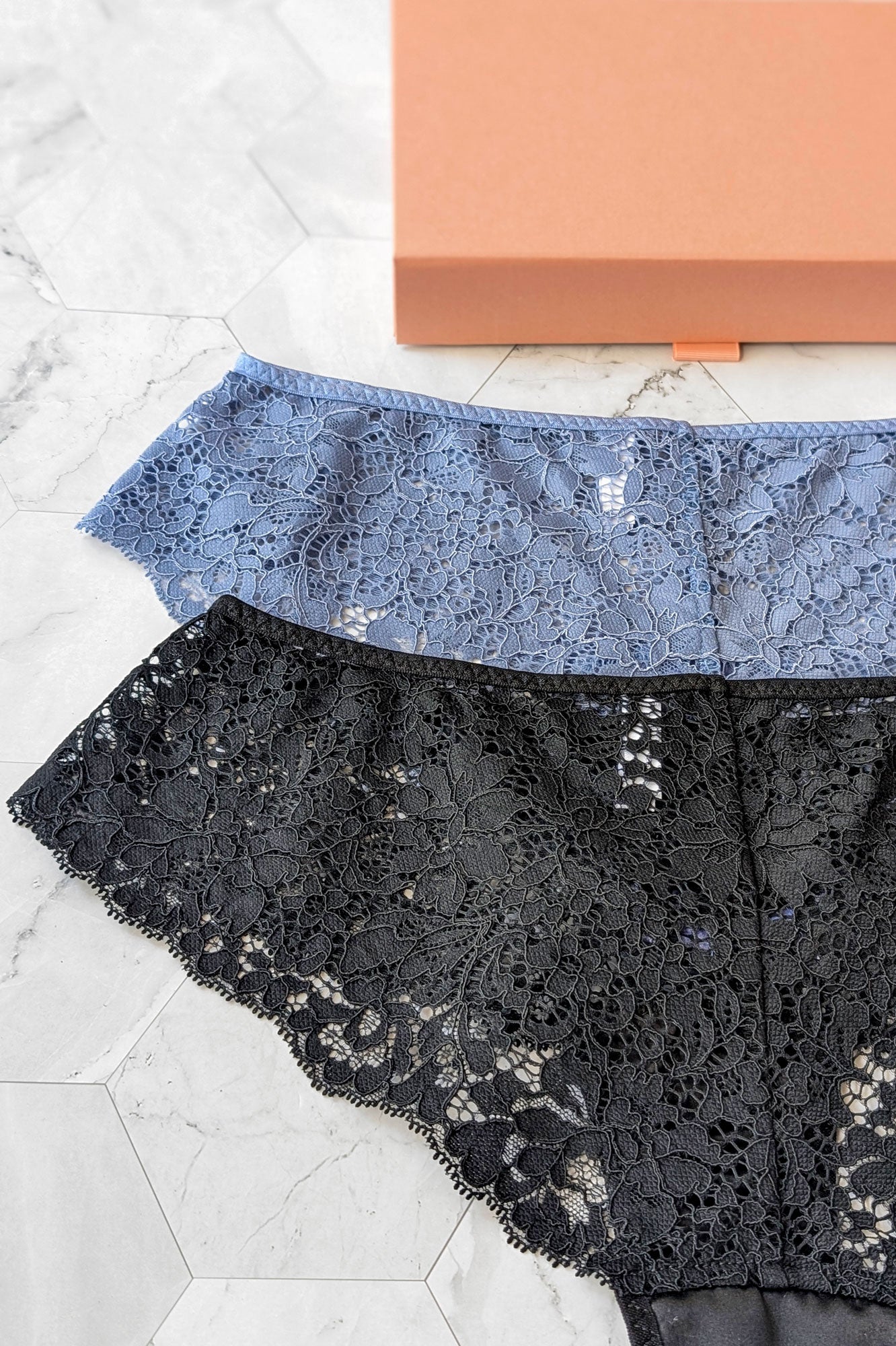 Closeup view of 2 pairs of black and grey-blue lace underwear by luxury lingerie designer Angela Friedman
