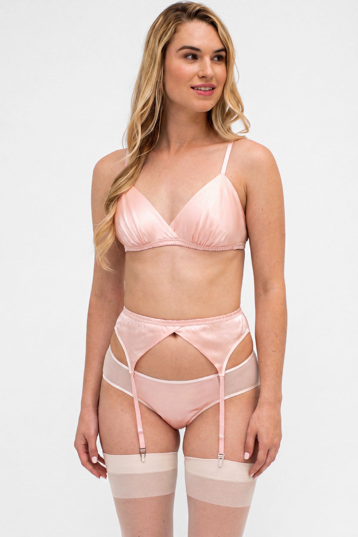 Woman wearing a pink lingerie set with a suspender belt and white stockings