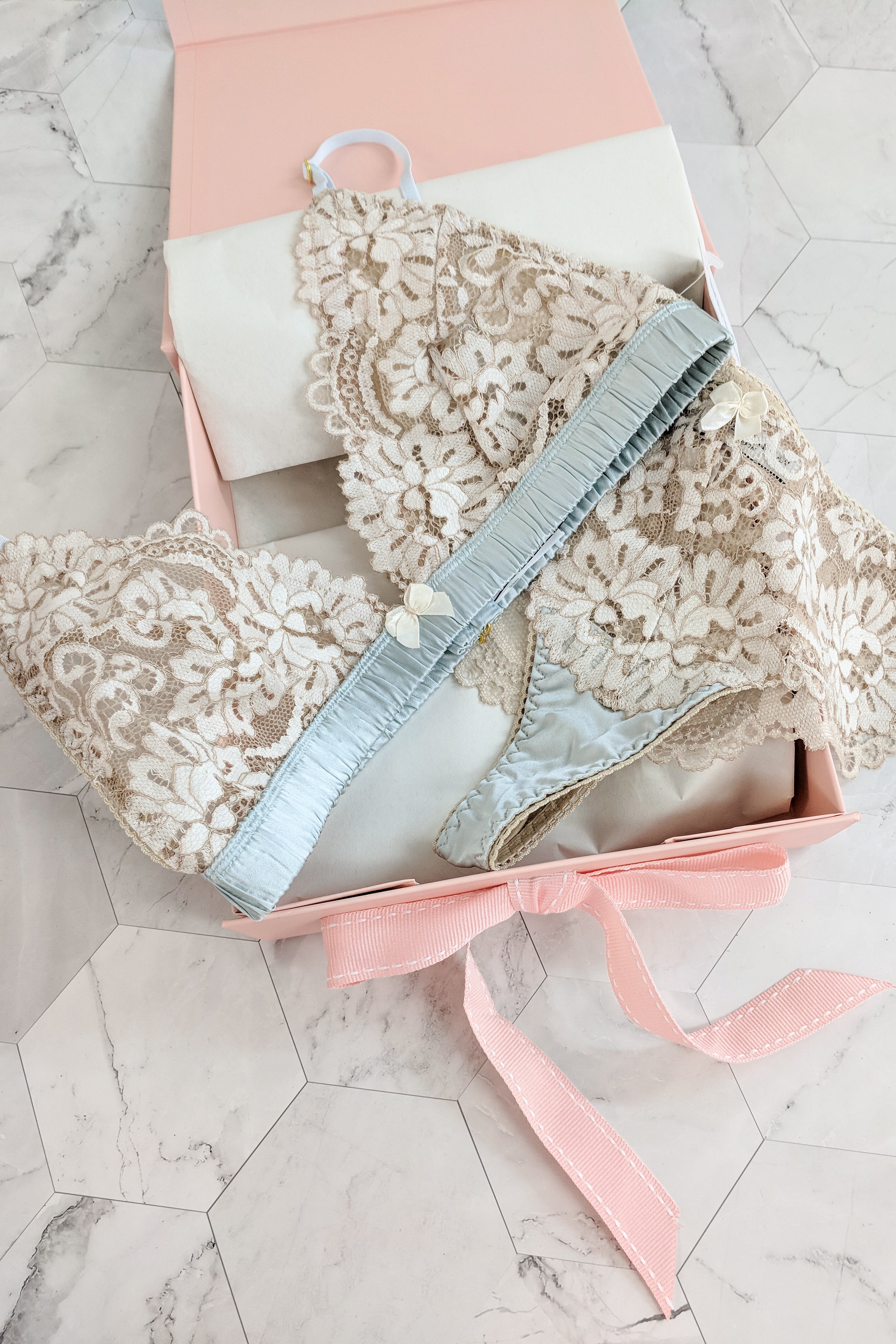 Flat lay of a luxury blue and cream lace bralette and thong panties