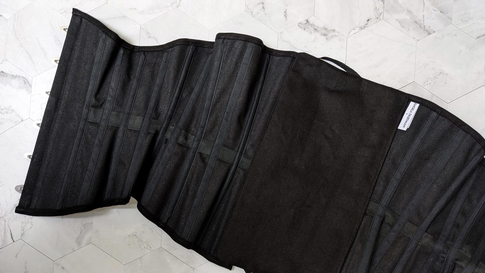 Black cotton underbust corset, showing the interior boning channels with steel bones
