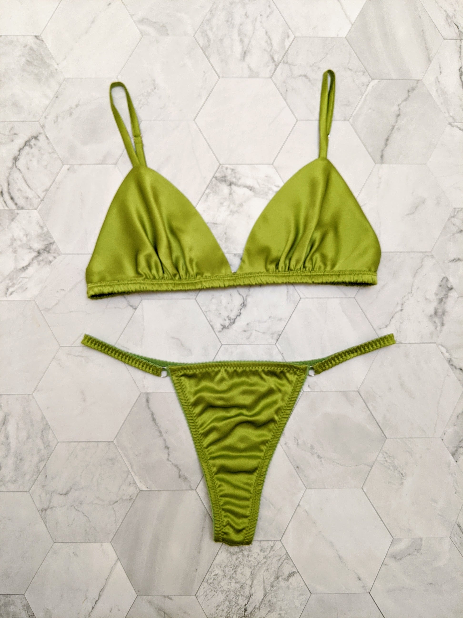 Luxury, designer lingerie set in green silk satin, including a bralette and thong