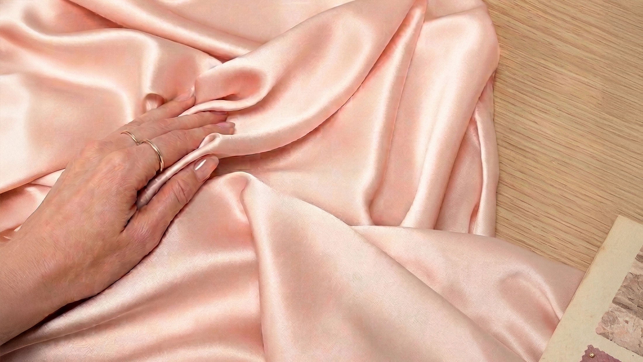 Hand holding pink silk satin fabric in the fashion design studio