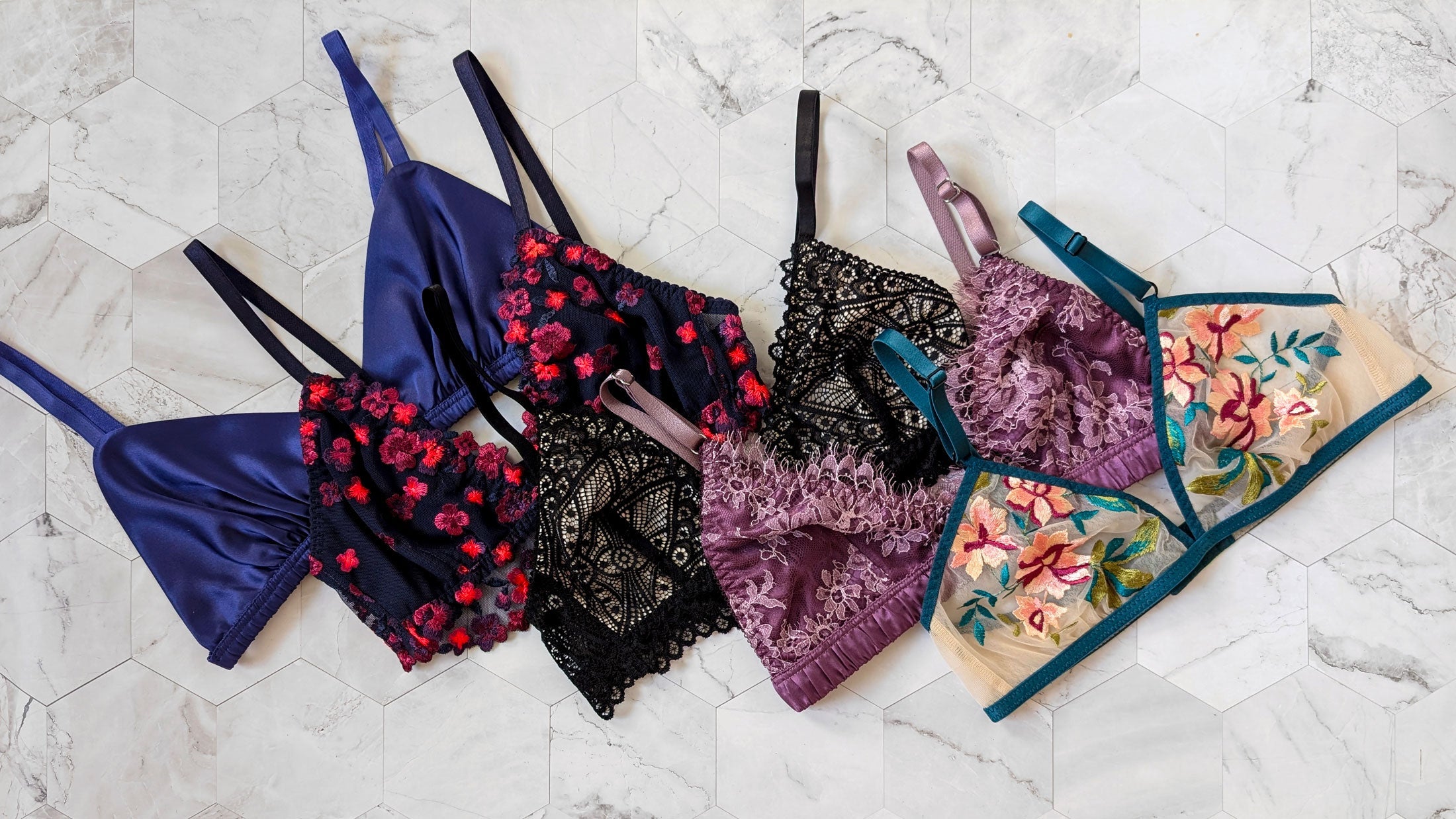 Luxury bralettes handmade in silk, satin, and lace in blue, pink, black, purple, and nude with floral embroidery