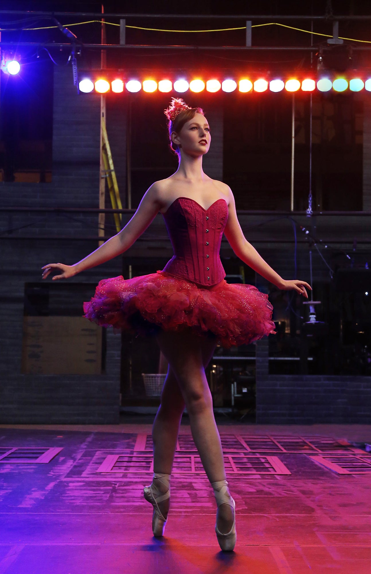 Firebird tutu design with a red corset bodice on a ballerina onstage in front of bright stage lights