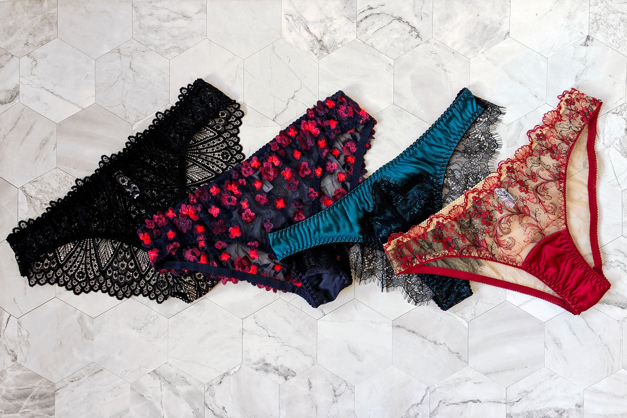 4 women's underwear pairs in silk with french lace and colorful embroidered overlays in navy blue, black, bright teal, and red