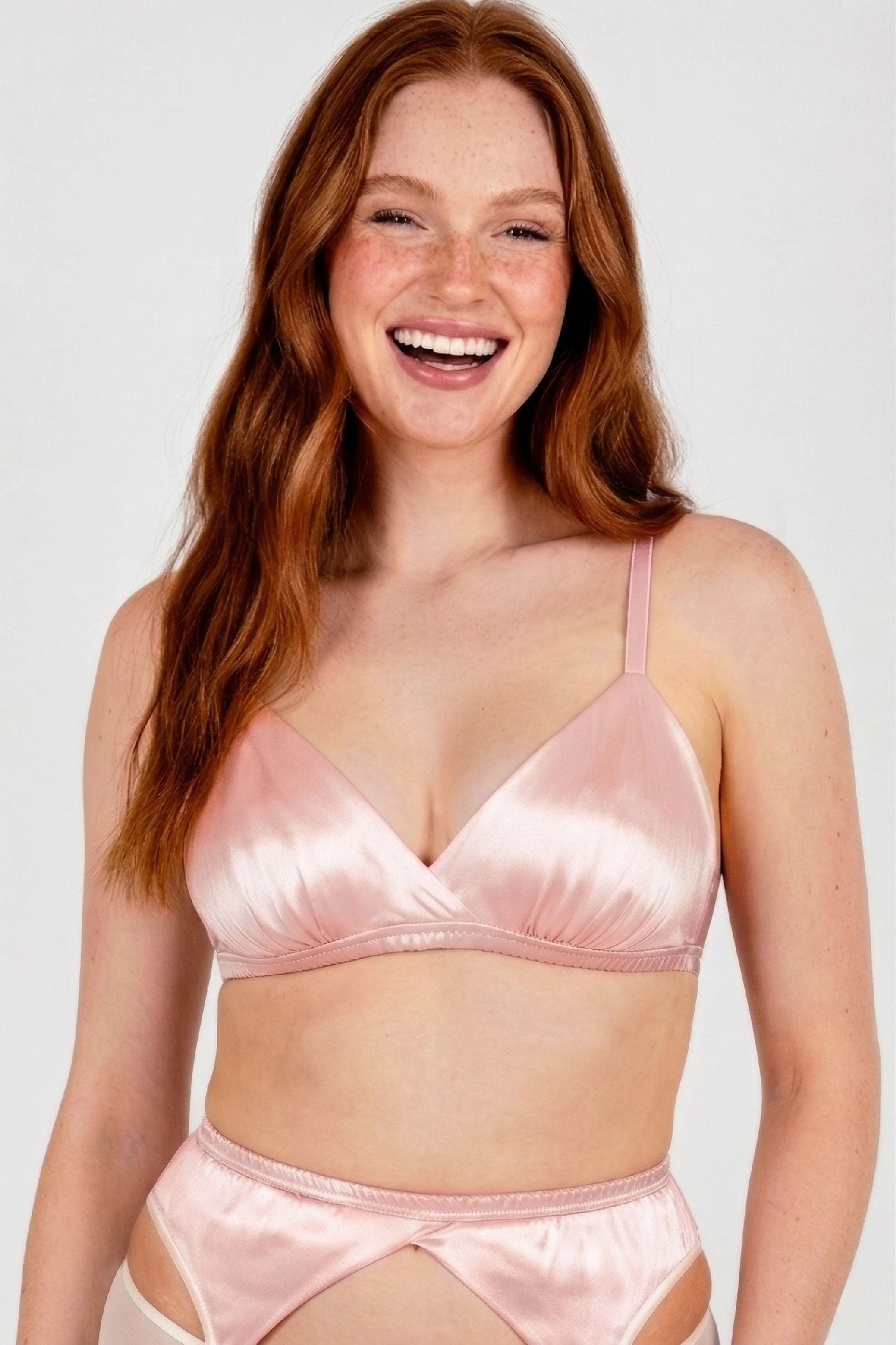 Redhead model wearing a pink silk triangle bralet and lingerie set