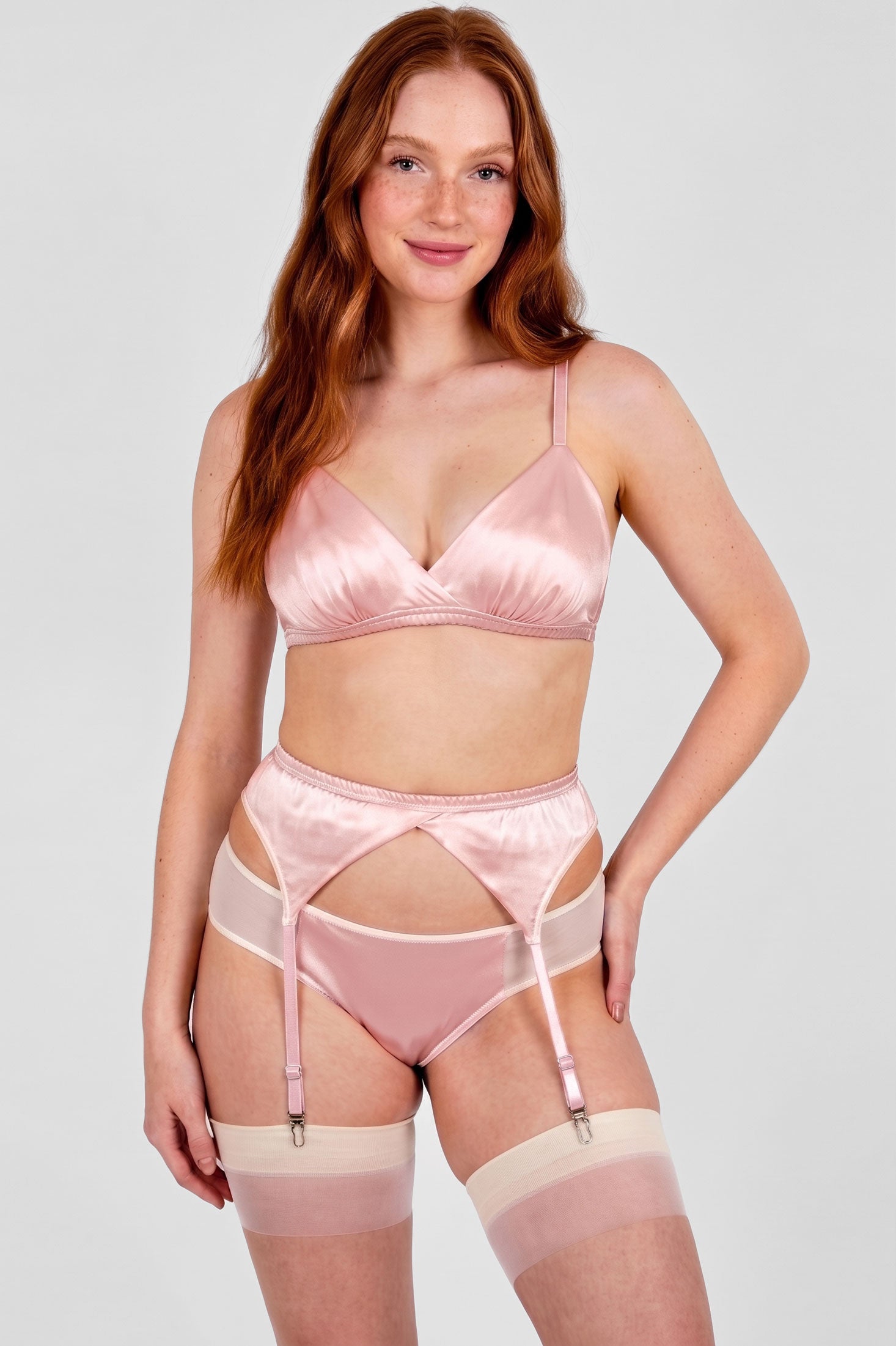 Woman wearing a light pink satin lingerie set with suspender belt and stockings