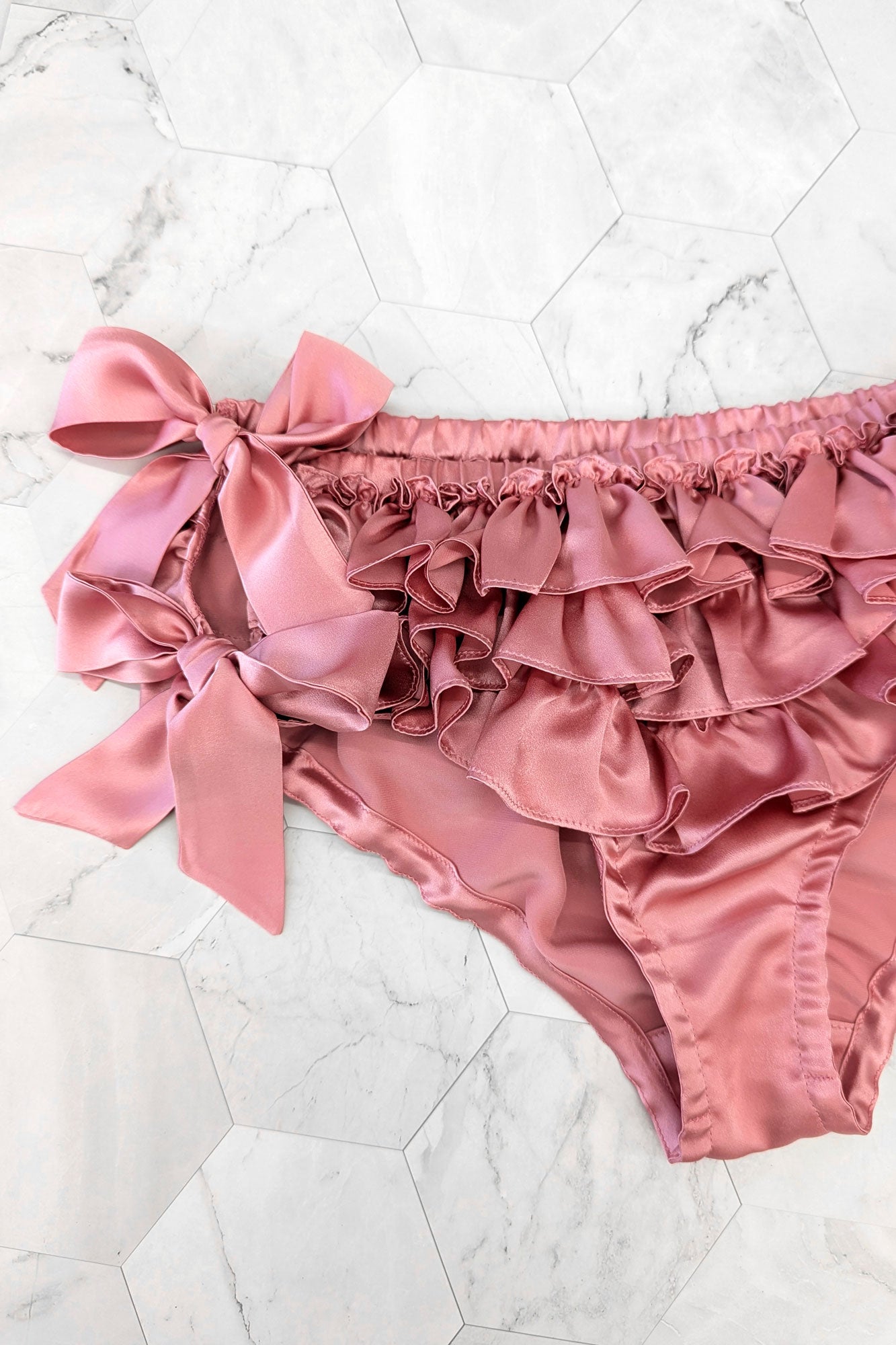 Pink silk ruffled panties and bow detail close up