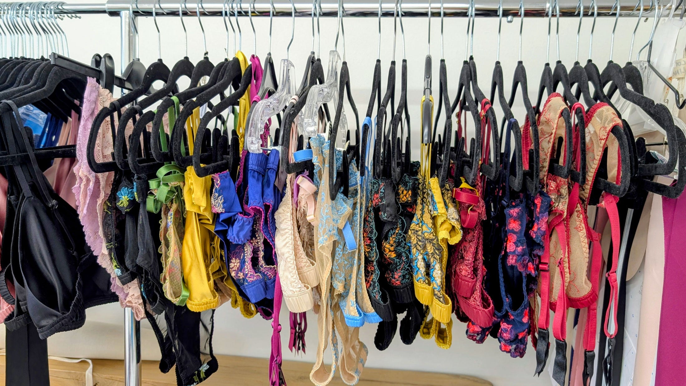 Rack of colorful silk and lace lingerie designs on hangers in a store setting