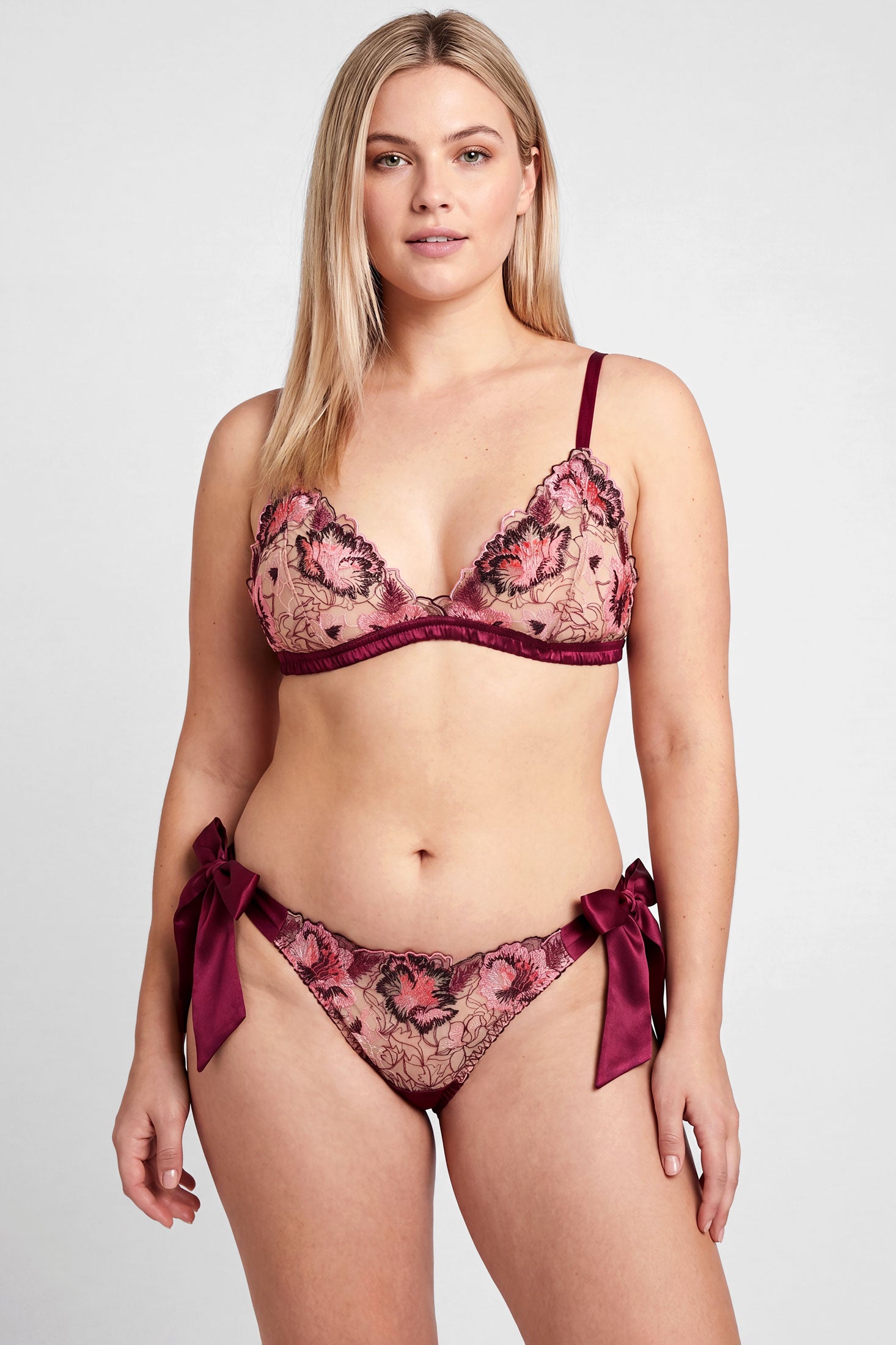 Woman wearing a burgundy lace lingerie set with silk bows and trims