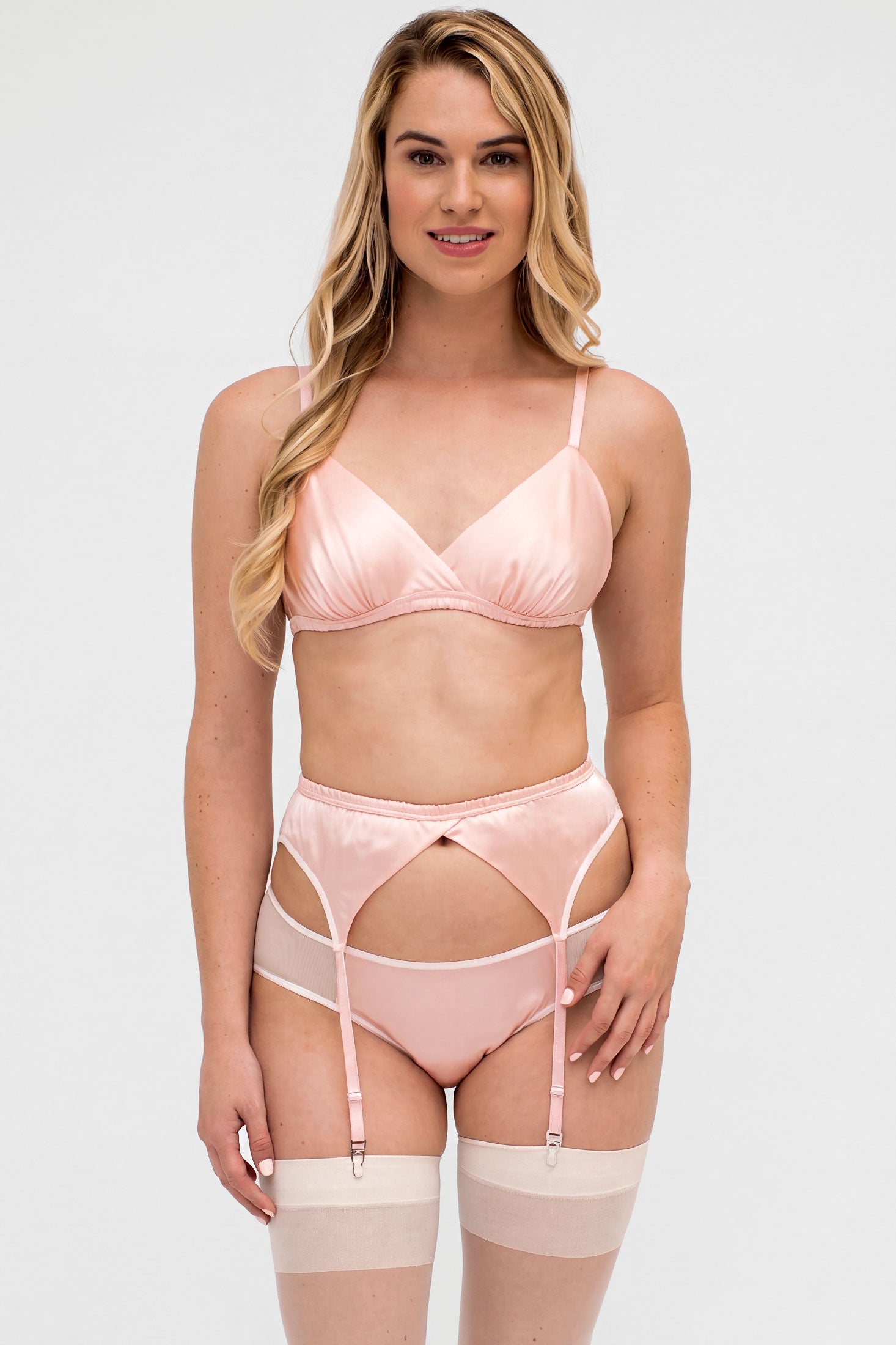Woman wearing a pink lingerie set with stockings on a white background