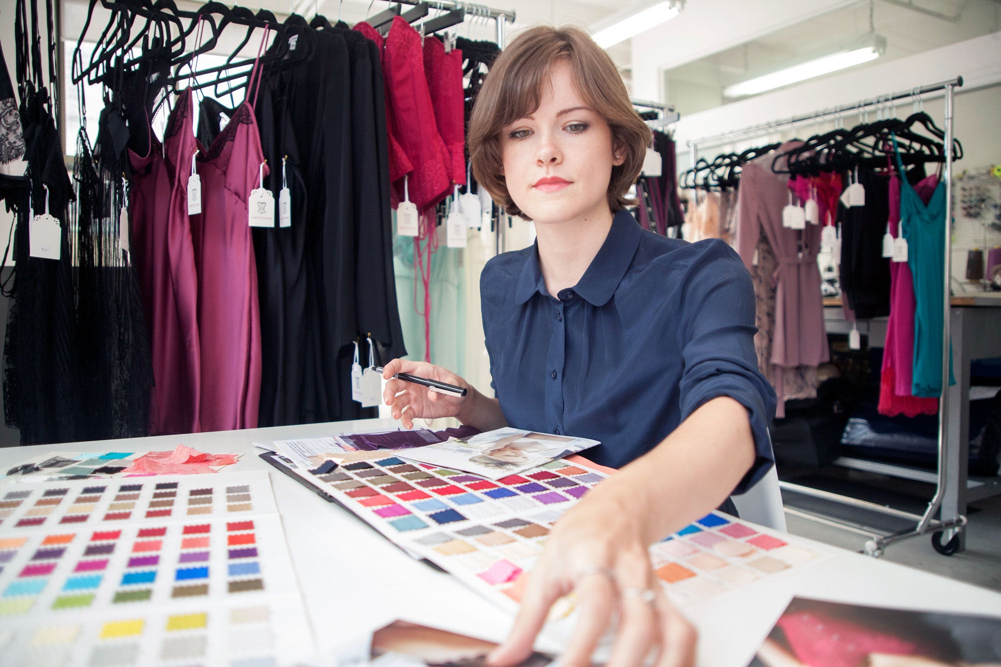 Angela Friedman, lingerie designer, in her showroom with silk swatches and a garment rack showing silk slips and robes on display
